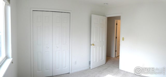 unfurnished bedroom featuring light colored carpet and a closet