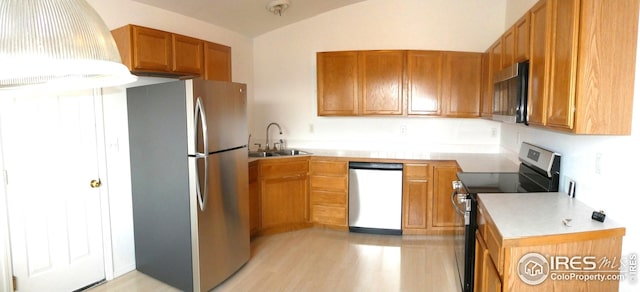 kitchen with lofted ceiling, appliances with stainless steel finishes, sink, and light hardwood / wood-style flooring