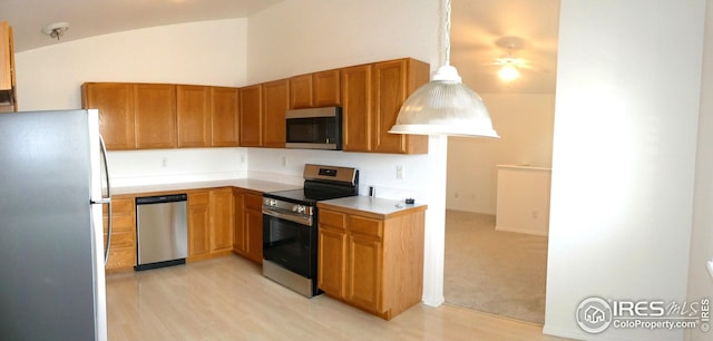 kitchen featuring hanging light fixtures, vaulted ceiling, light colored carpet, and appliances with stainless steel finishes