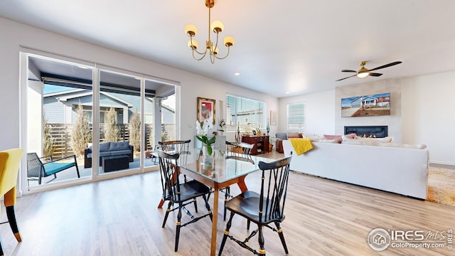 dining area with ceiling fan with notable chandelier, light wood finished floors, recessed lighting, and a fireplace