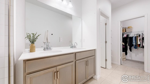 full bath with a sink, a spacious closet, tile patterned floors, and double vanity
