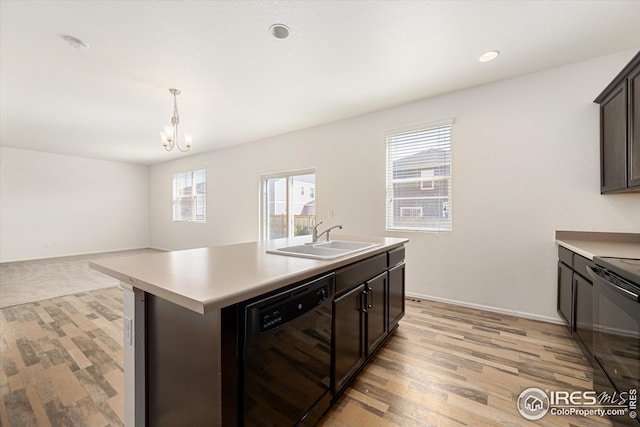 kitchen with pendant lighting, an island with sink, sink, black appliances, and dark brown cabinets