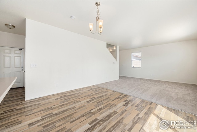 empty room with an inviting chandelier and wood-type flooring