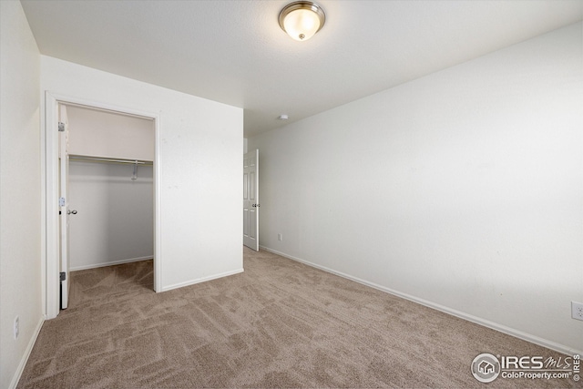 unfurnished bedroom featuring a walk in closet, light carpet, and a closet