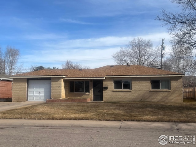 single story home with brick siding, a shingled roof, concrete driveway, an attached garage, and a front yard