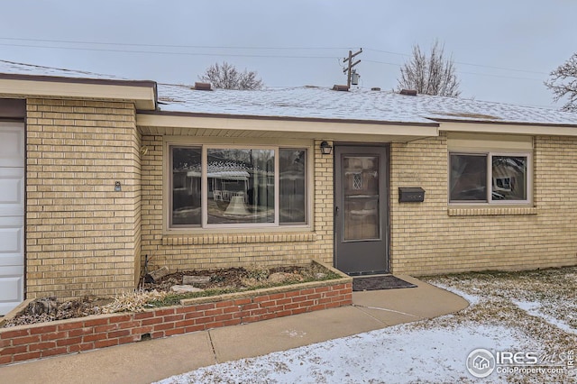 entrance to property with a garage and brick siding