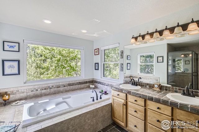 bathroom with tile patterned floors, vanity, separate shower and tub, and a wealth of natural light