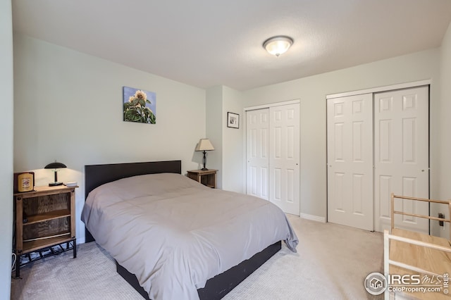 bedroom featuring carpet and two closets