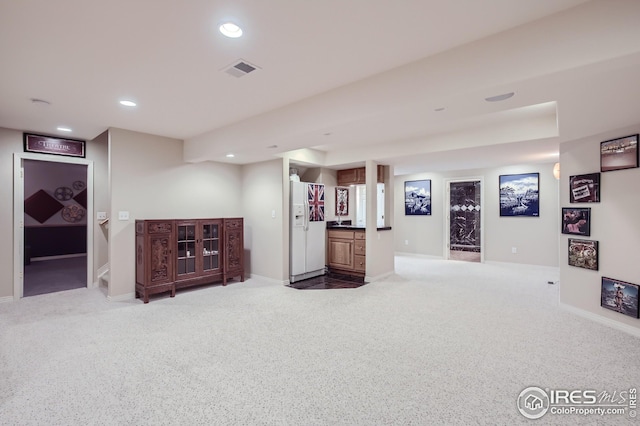 basement featuring carpet flooring and white fridge with ice dispenser