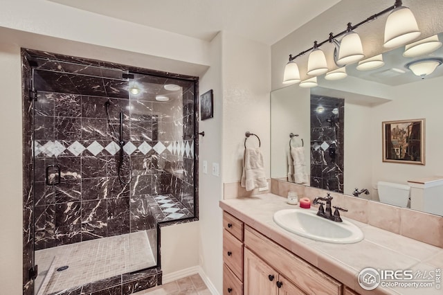 bathroom with tiled shower, vanity, and toilet