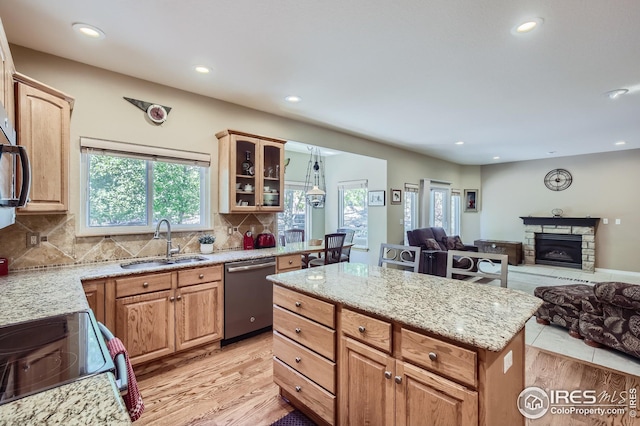 kitchen featuring dishwasher, sink, light stone counters, and light hardwood / wood-style flooring