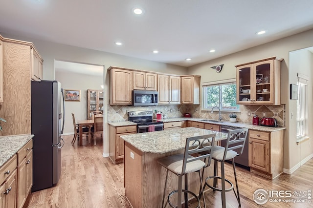 kitchen with sink, decorative backsplash, a center island, stainless steel appliances, and light wood-type flooring