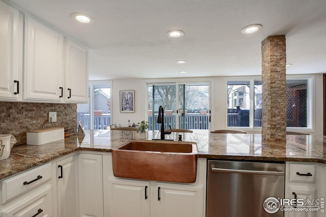 kitchen featuring decorative columns, a sink, backsplash, dishwasher, and white cabinets