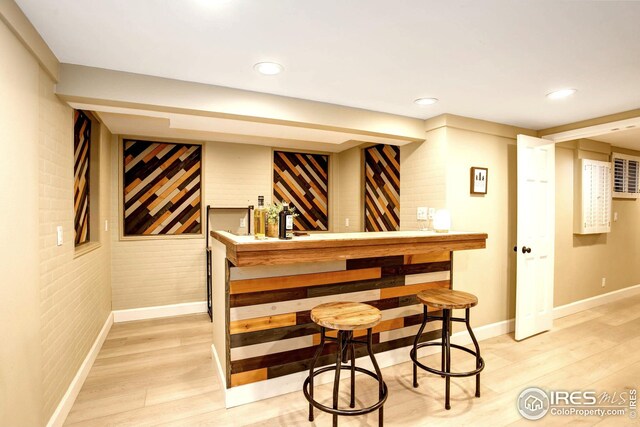 bar featuring recessed lighting, a dry bar, brick wall, and light wood-type flooring