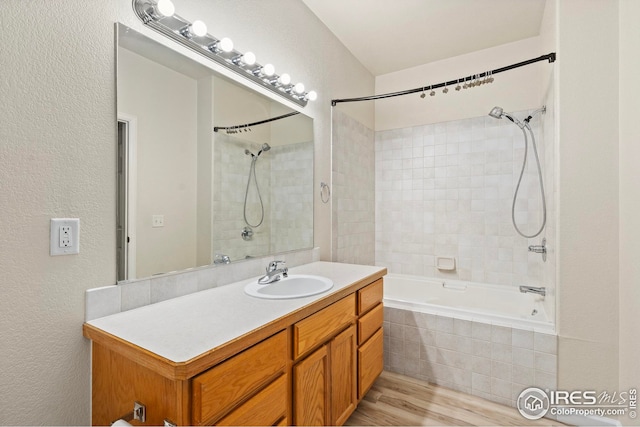 bathroom with tiled shower / bath combo, vanity, and wood-type flooring