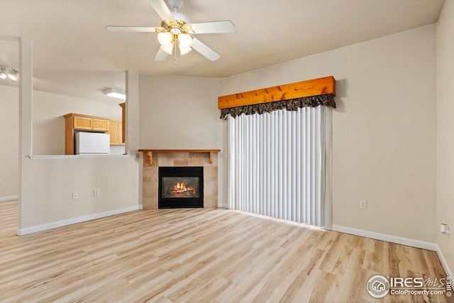 unfurnished living room with a fireplace, ceiling fan, and light wood-type flooring