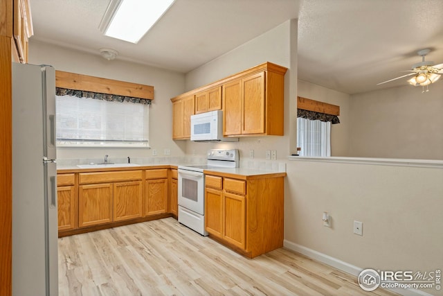 kitchen featuring ceiling fan, sink, white appliances, and light hardwood / wood-style floors