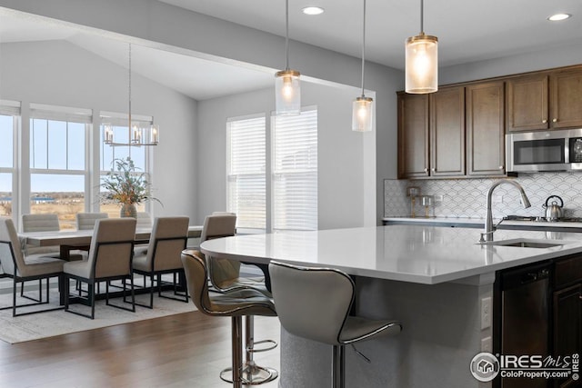 kitchen featuring pendant lighting, a sink, backsplash, appliances with stainless steel finishes, and lofted ceiling