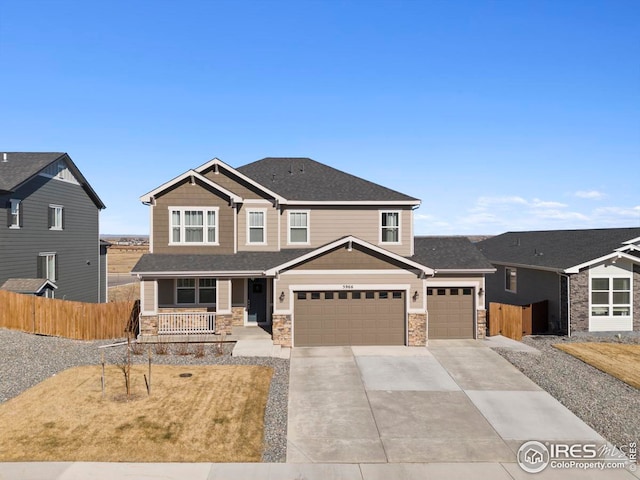 craftsman inspired home with fence, driveway, covered porch, a garage, and stone siding