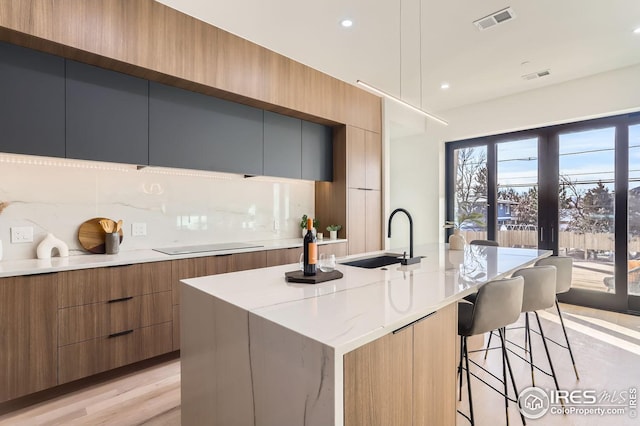 kitchen featuring tasteful backsplash, a center island with sink, a kitchen breakfast bar, and light wood-type flooring