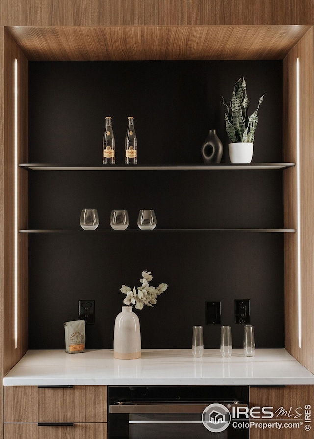 bar featuring tasteful backsplash, hanging light fixtures, sink, and light wood-type flooring