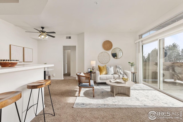 carpeted living area with a ceiling fan, visible vents, and baseboards