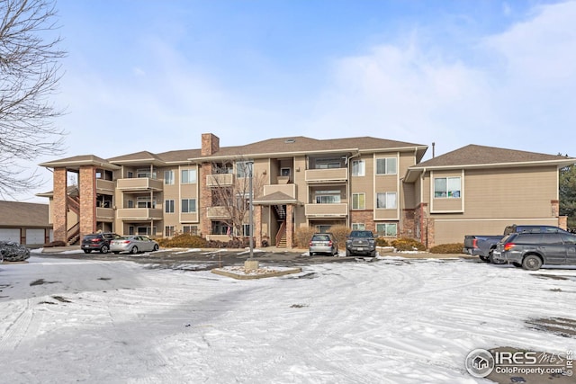 snow covered property with uncovered parking