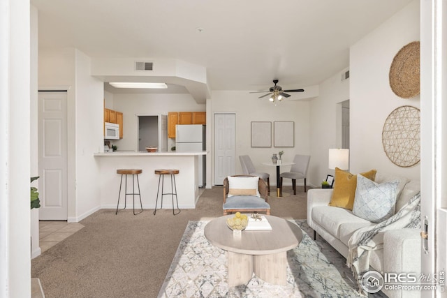 living area with a ceiling fan, light colored carpet, visible vents, and baseboards