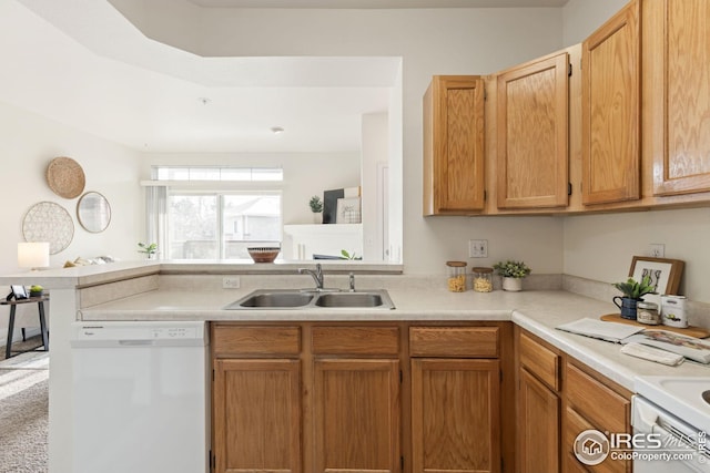 kitchen with light countertops, dishwasher, a peninsula, and a sink