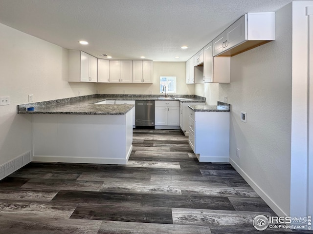 kitchen featuring visible vents, a peninsula, dark wood-type flooring, a textured ceiling, and stainless steel dishwasher