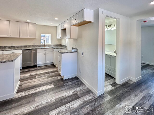 kitchen with baseboards, dark wood finished floors, a sink, a textured ceiling, and stainless steel dishwasher