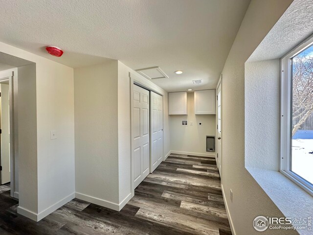 hallway featuring dark wood-style floors, attic access, a textured ceiling, and baseboards