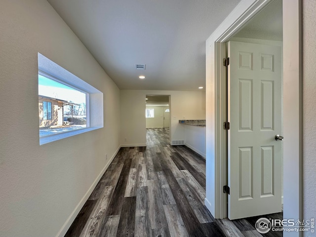 hall with visible vents, baseboards, and wood finished floors