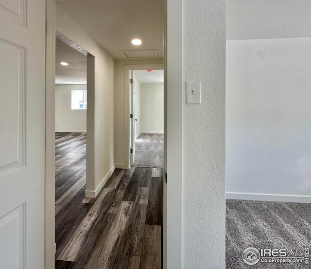 corridor with a textured wall, baseboards, and dark wood-style flooring
