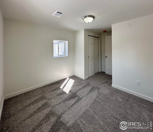 unfurnished room with visible vents, a textured ceiling, baseboards, and carpet floors