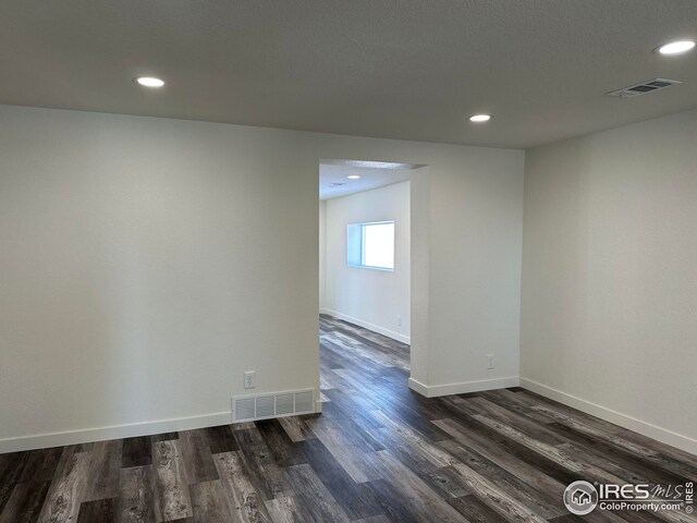 spare room with recessed lighting, baseboards, visible vents, and dark wood-style flooring