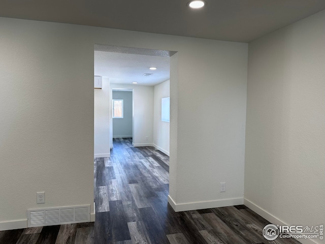 hall with dark wood finished floors, visible vents, recessed lighting, and baseboards