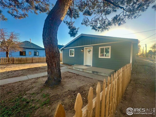 view of front of house with a porch, board and batten siding, and fence