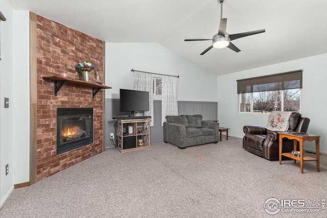 living room featuring ceiling fan, lofted ceiling, carpet floors, and a brick fireplace