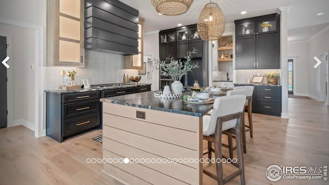 3806 Bridle Ridge Cir, Severance, CO 80524 - kitchen with custom range hood, light wood-style flooring, decorative backsplash, ornamental molding, and glass insert cabinets