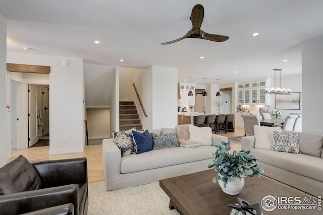 living room featuring light hardwood / wood-style floors and ceiling fan with notable chandelier