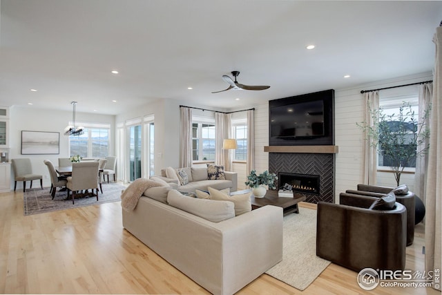 living room with light hardwood / wood-style flooring, ceiling fan, and a large fireplace