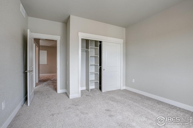 unfurnished bedroom with a closet and light colored carpet