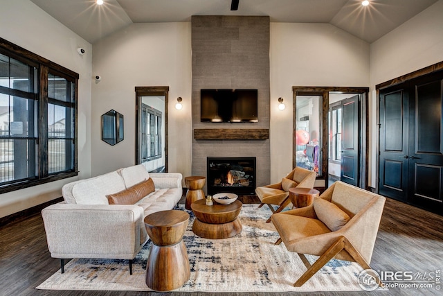 living room with a tiled fireplace, vaulted ceiling, and dark hardwood / wood-style flooring