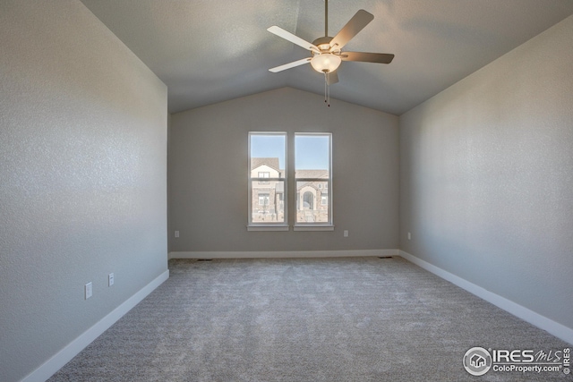 carpeted spare room with a textured ceiling, vaulted ceiling, and ceiling fan