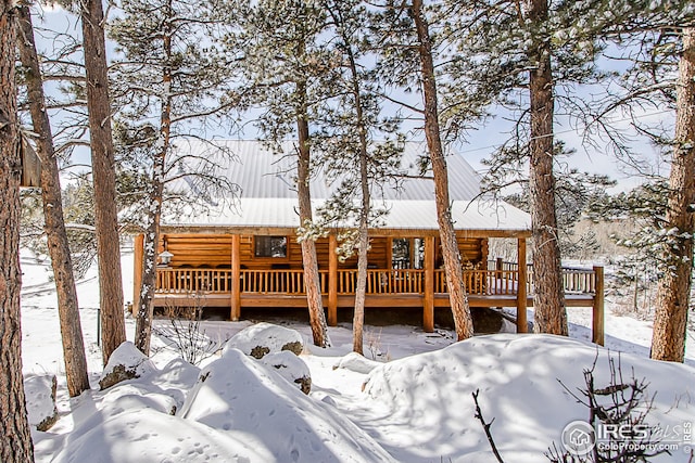 snow covered rear of property featuring a wooden deck and metal roof