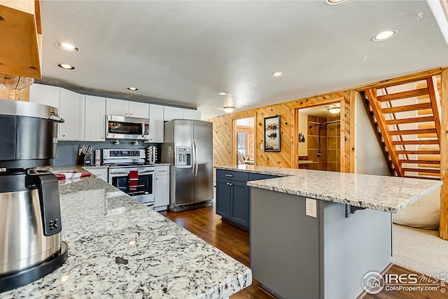 kitchen featuring appliances with stainless steel finishes, a center island, recessed lighting, white cabinets, and a kitchen breakfast bar