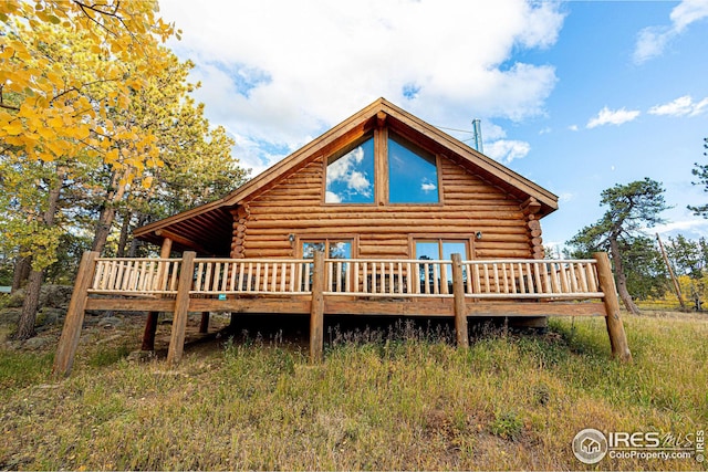 back of house with log exterior and a wooden deck
