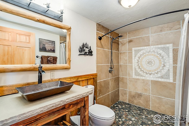 bathroom featuring tiled shower, vanity, and toilet