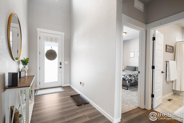 foyer entrance featuring visible vents, baseboards, and wood finished floors